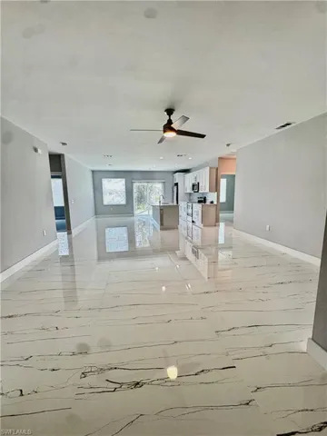 Unfurnished living room featuring ceiling fan and light marble finish flooring