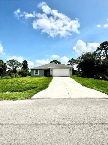 Ranch-style home featuring a garage, concrete driveway, a front lawn, and stucco siding