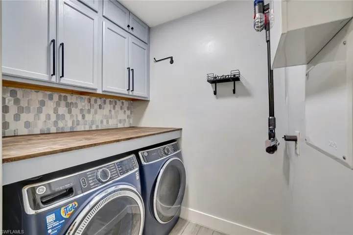 Laundry area with washer and clothes dryer, cabinet space, and light wood-style floors