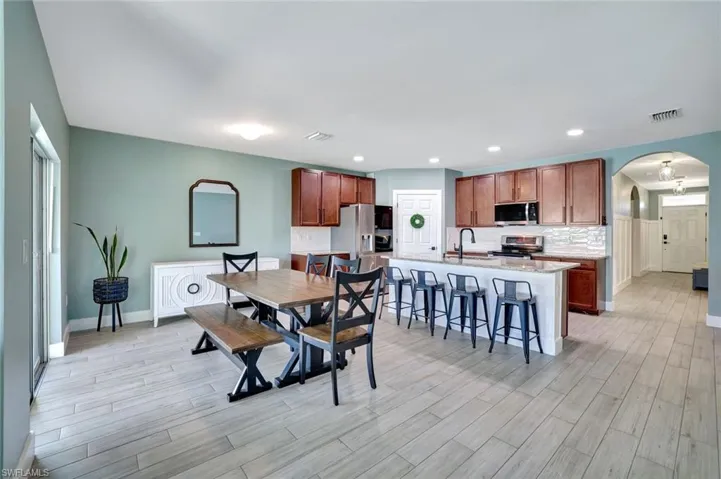 Dining space featuring arched walkways, light wood-type flooring, and recessed lighting