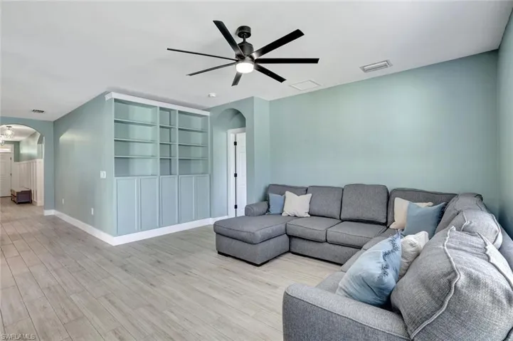 Living room featuring arched walkways, a ceiling fan, and light wood finished floors