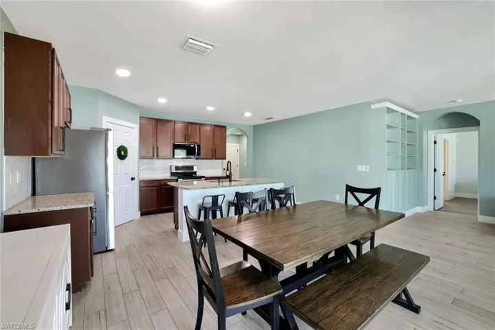 Dining space with arched walkways, light wood-type flooring, and recessed lighting