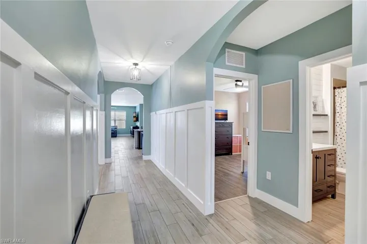 Corridor featuring arched walkways and light wood-style flooring