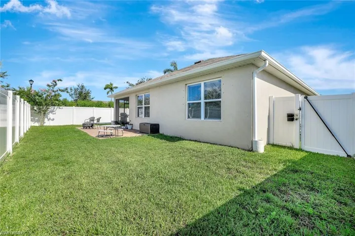 Rear view of house featuring stucco siding, a patio, a fenced backyard, and a gate