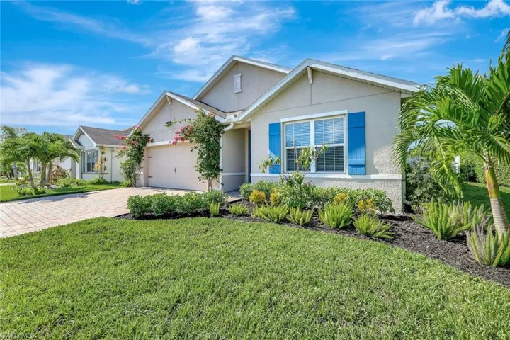 View of front facade featuring stucco siding, a front yard, a garage, and decorative driveway