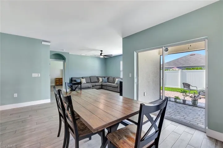 Dining space with light wood finished floors, ceiling fan, and arched walkways