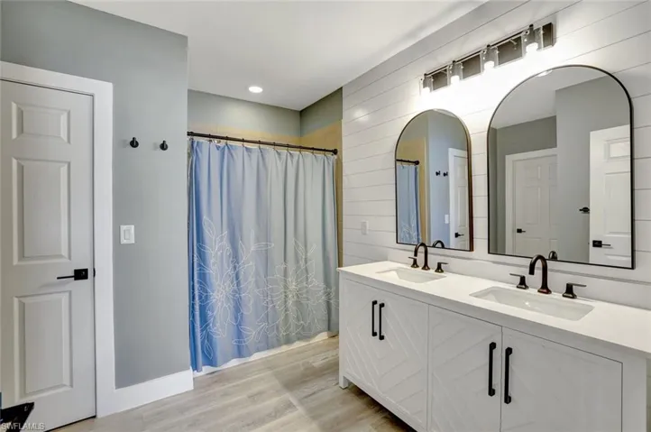 Bathroom featuring double vanity, wood finished floors, and a shower with shower curtain