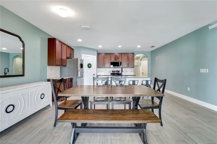 Dining area with arched walkways, light wood-style floors, and recessed lighting