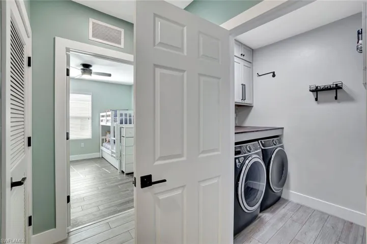 Laundry room with cabinet space, washing machine and dryer, a ceiling fan, and light wood-type flooring