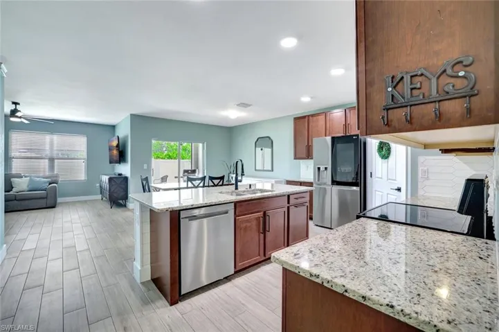 Kitchen with stainless steel appliances, an island with sink, open floor plan, light wood-style floors, and recessed lighting