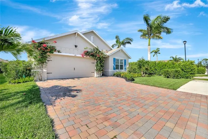 Single story home featuring a garage, decorative driveway, stucco siding, and a front yard