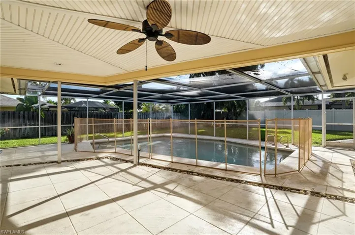 View of swimming pool with glass enclosure, a sunroom, a patio, a fenced backyard, and ceiling fan