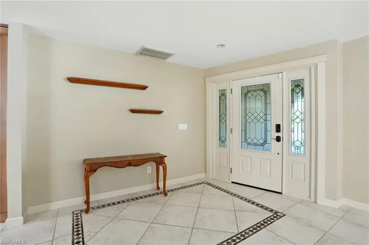 Foyer entrance with light tile patterned floors and inlaid floor details