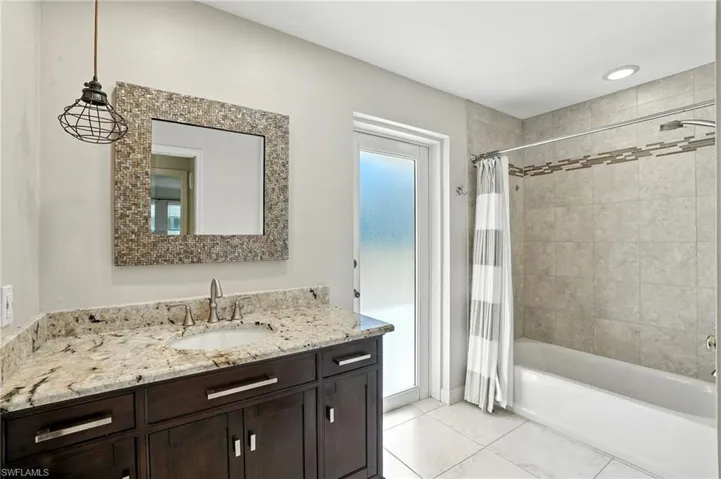 Bathroom with shower / tub combo with curtain, vanity, and light tile patterned flooring
