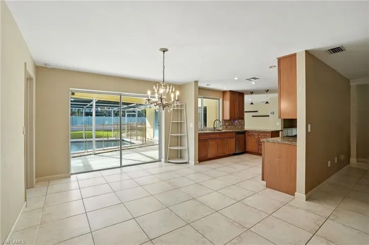 Kitchen featuring brown cabinets, hanging light fixtures, light tile patterned flooring, a chandelier, and recessed lighting
