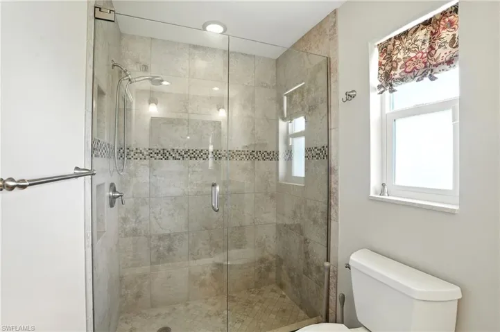 Full bathroom featuring toilet and a shower stall