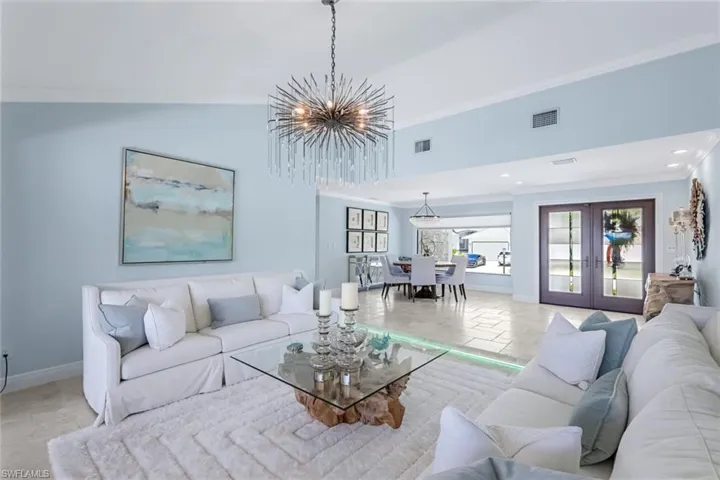 Formal living room looking toward double door hurricane impact entry. Multi colored custom lighting on floor.