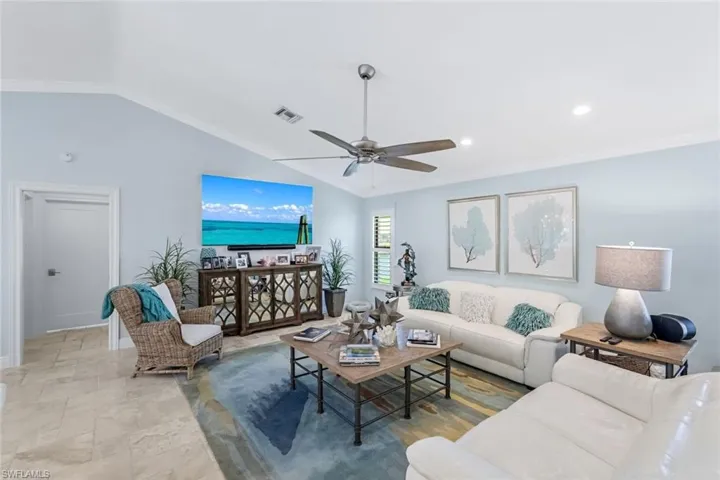 Living room featuring crown molding, ceiling fan, and vaulted ceiling