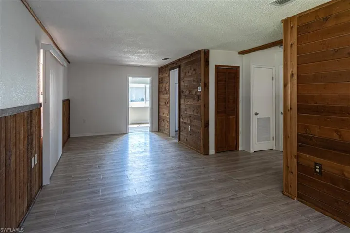 Spare room featuring a textured ceiling, wood-type flooring, and wood walls