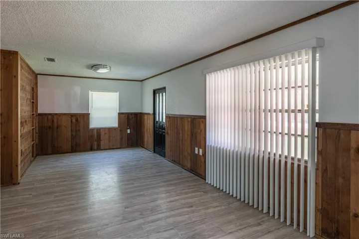 Empty room featuring a textured ceiling, wood walls, and hardwood / wood-style floors