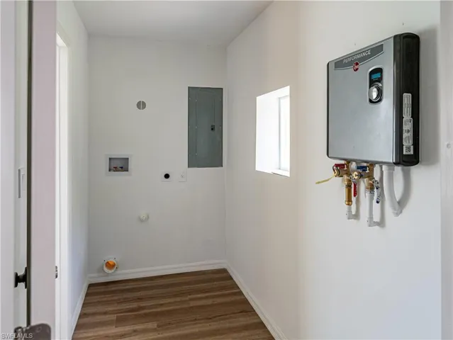 Clothes washing area featuring hookup for a washing machine, hookup for an electric dryer, water heater, and dark hardwood / wood-style floors