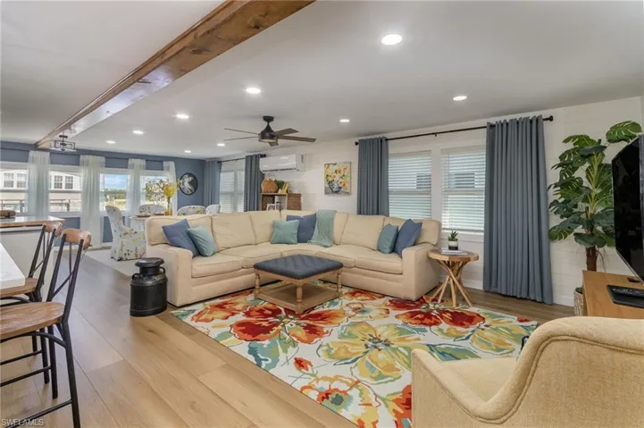 Living room featuring wood finished floors, ceiling fan, recessed lighting, and a wall mounted AC
