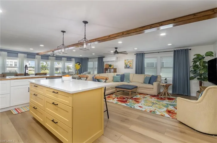 Kitchen featuring light wood-style floors, open floor plan, healthy amount of natural light, beam ceiling, and recessed lighting
