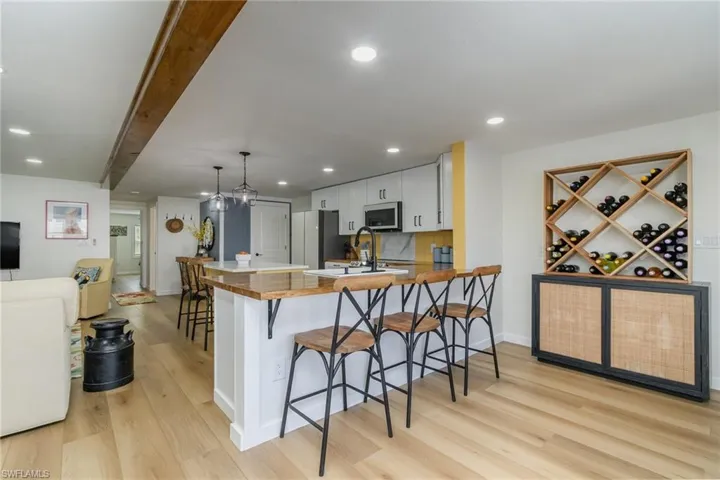 Kitchen featuring light wood-type flooring, a kitchen bar, freestanding refrigerator, a peninsula, and white cabinets