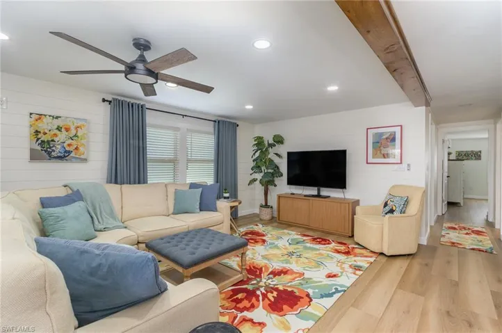 Living area featuring ceiling fan, light wood finished floors, recessed lighting, and wood walls