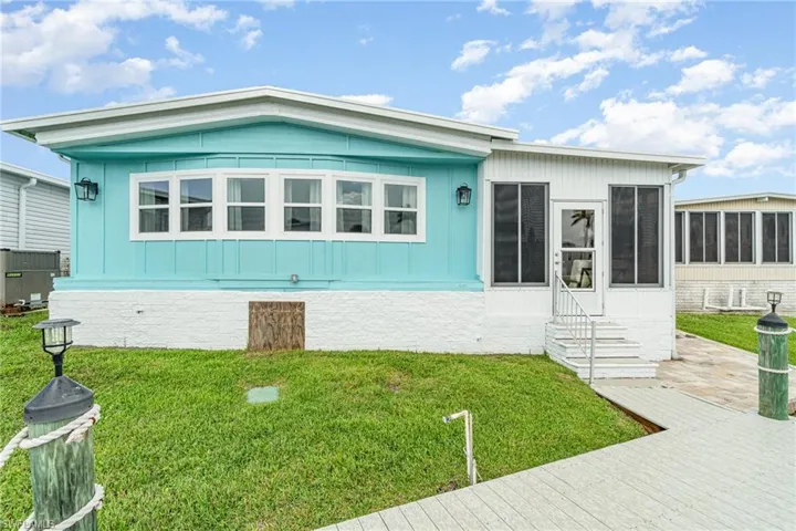 Manufactured / mobile home featuring a sunroom, entry steps, and a front yard