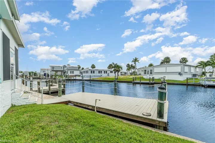 Dock area with a water view, a lawn, and a residential view