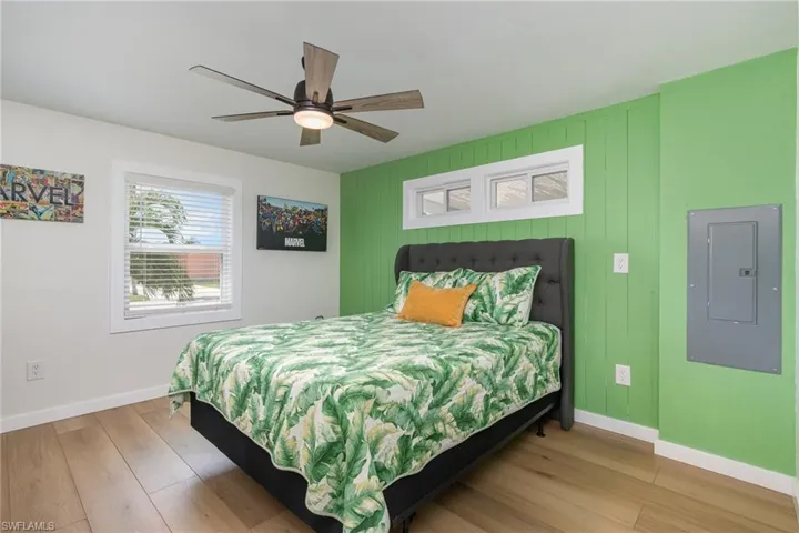 Bedroom with electric panel, wood finished floors, and ceiling fan