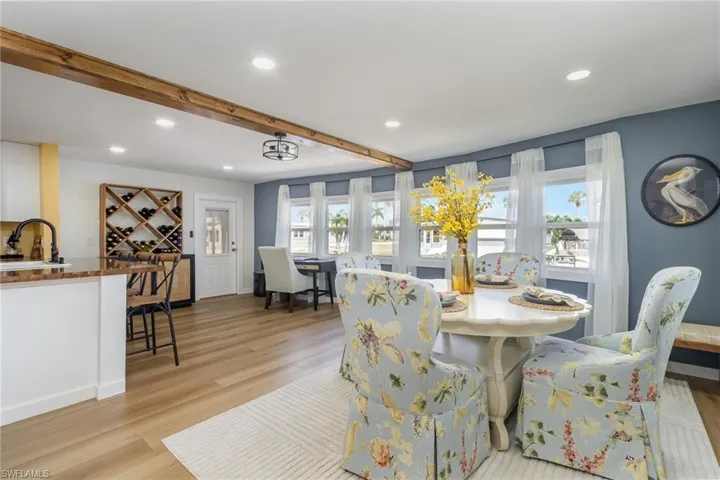 Dining room with light wood-type flooring, recessed lighting, beamed ceiling, and bar