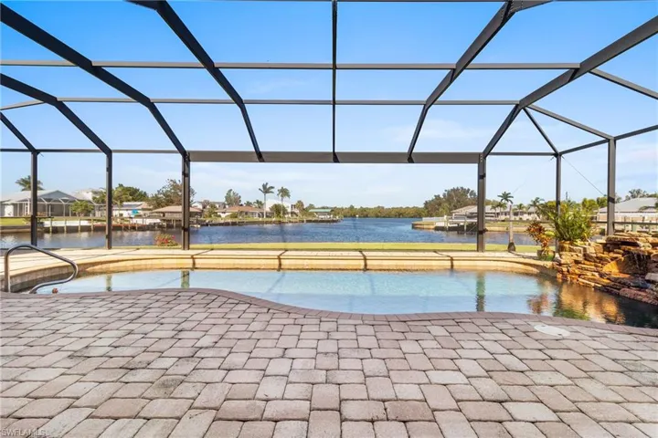 View of swimming pool featuring glass enclosure, a patio area, and a water view
