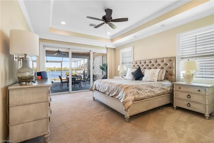Bedroom featuring access to outside, a raised ceiling, light colored carpet, and multiple windows
