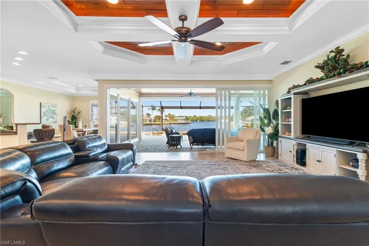 Living room with ceiling fan, ornamental molding, wood ceiling, and a tray ceiling