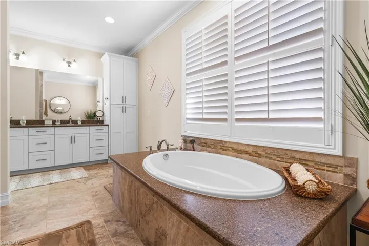 Bathroom featuring vanity, a bathtub, and ornamental molding