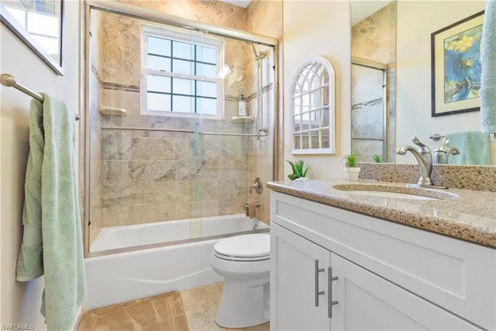 Full bathroom with tile patterned floors, vanity, toilet, and combined bath / shower with glass door