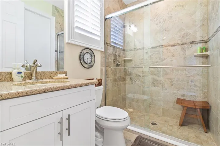 Bathroom with vanity, an enclosed shower, and toilet