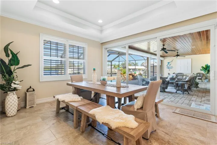 Dining space with a raised ceiling, ceiling fan, and ornamental molding