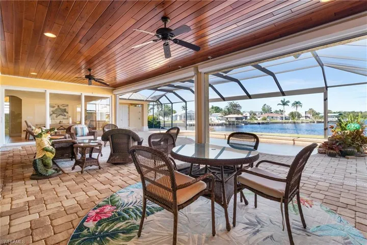 View of patio with a lanai, outdoor lounge area, ceiling fan, and a water view