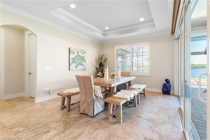 Dining area featuring a tray ceiling, a water view, and ornamental molding