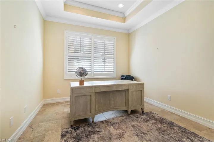 Office space featuring a raised ceiling and crown molding