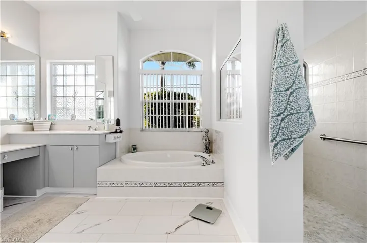 Bathroom featuring vanity, a bath, and a walk in shower