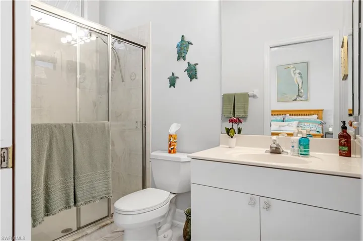 Ensuite bathroom featuring toilet, vanity, a stall shower, and connected bathroom