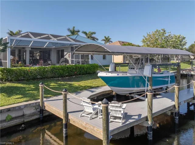 Dock area featuring a water view, a lawn, and boat lift
