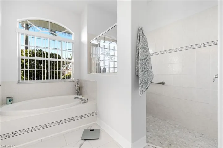 Full bath featuring a healthy amount of sunlight, baseboards, tiled shower, and a bath