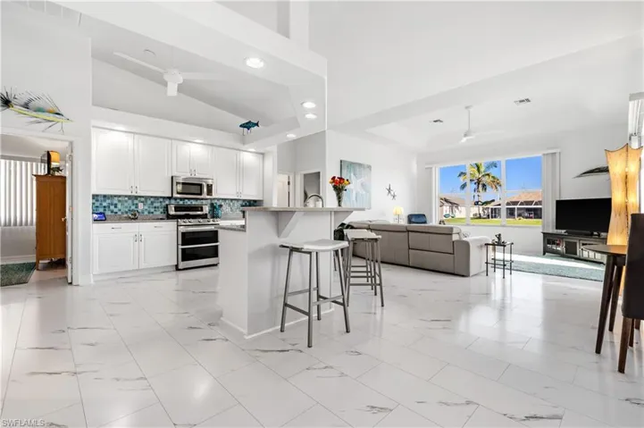 Kitchen with marble finish floor, open floor plan, ceiling fan, and stainless steel appliances