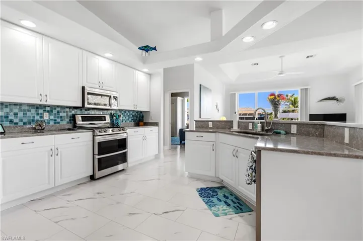 Kitchen featuring marble finish floor, a sink, stainless steel appliances, and tasteful backsplash