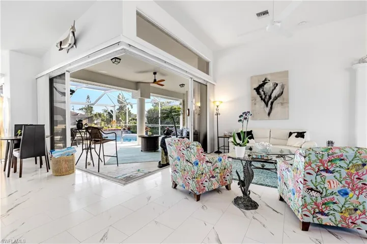 Living room with marble finish floor, ceiling fan, visible vents, and a sunroom